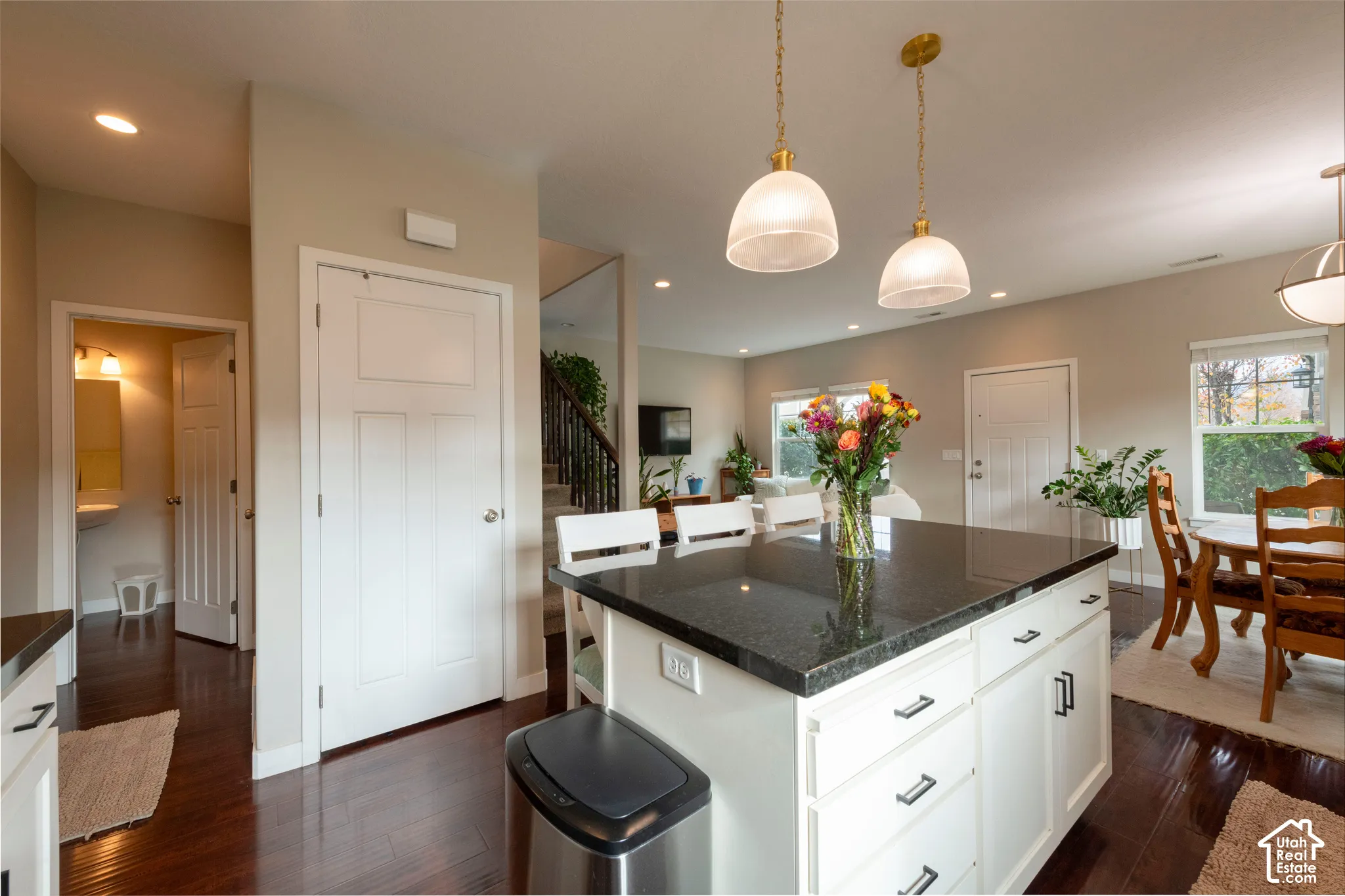 Kitchen island with dark countertop and white cabinetry, recessed lighting, wood-finish flooring, and pendant lighting