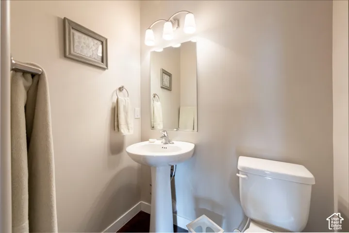 Pedestal sink with chrome faucet, wall-mounted mirror, and overhead vanity lighting