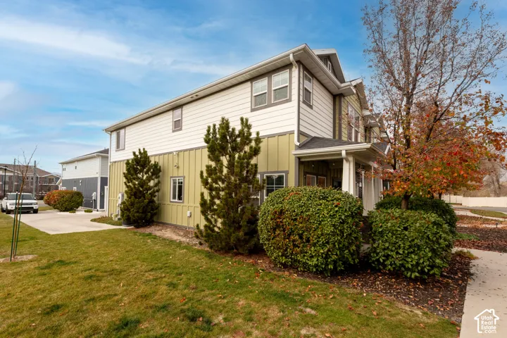 Multi-level exterior with board and batten siding, multiple windows, covered entry, and mature landscaping