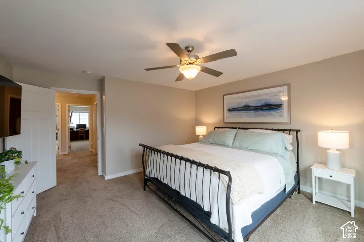 Carpeted bedroom with a ceiling fan, neutral wall paint, and a white paneled door