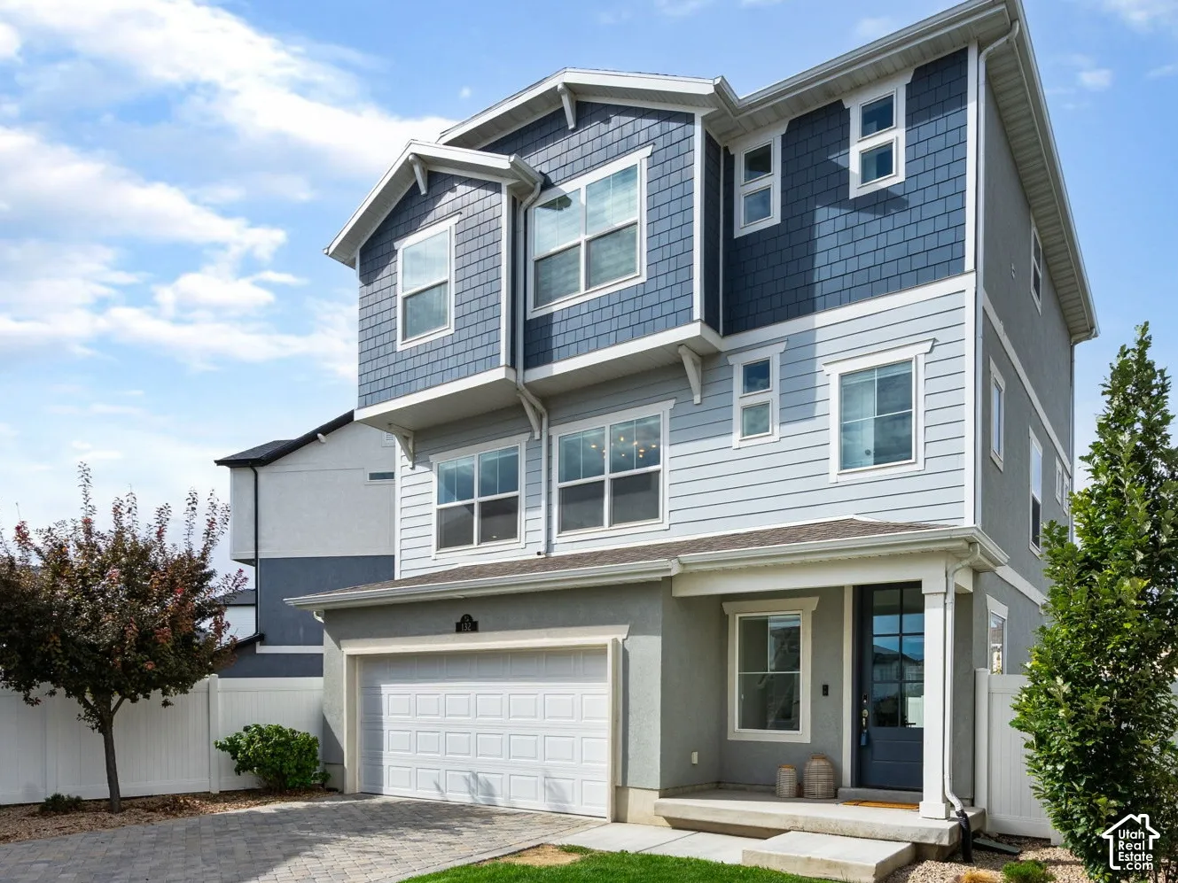 Modern exterior with mixed siding, attached garage, paver driveway, and a covered entry