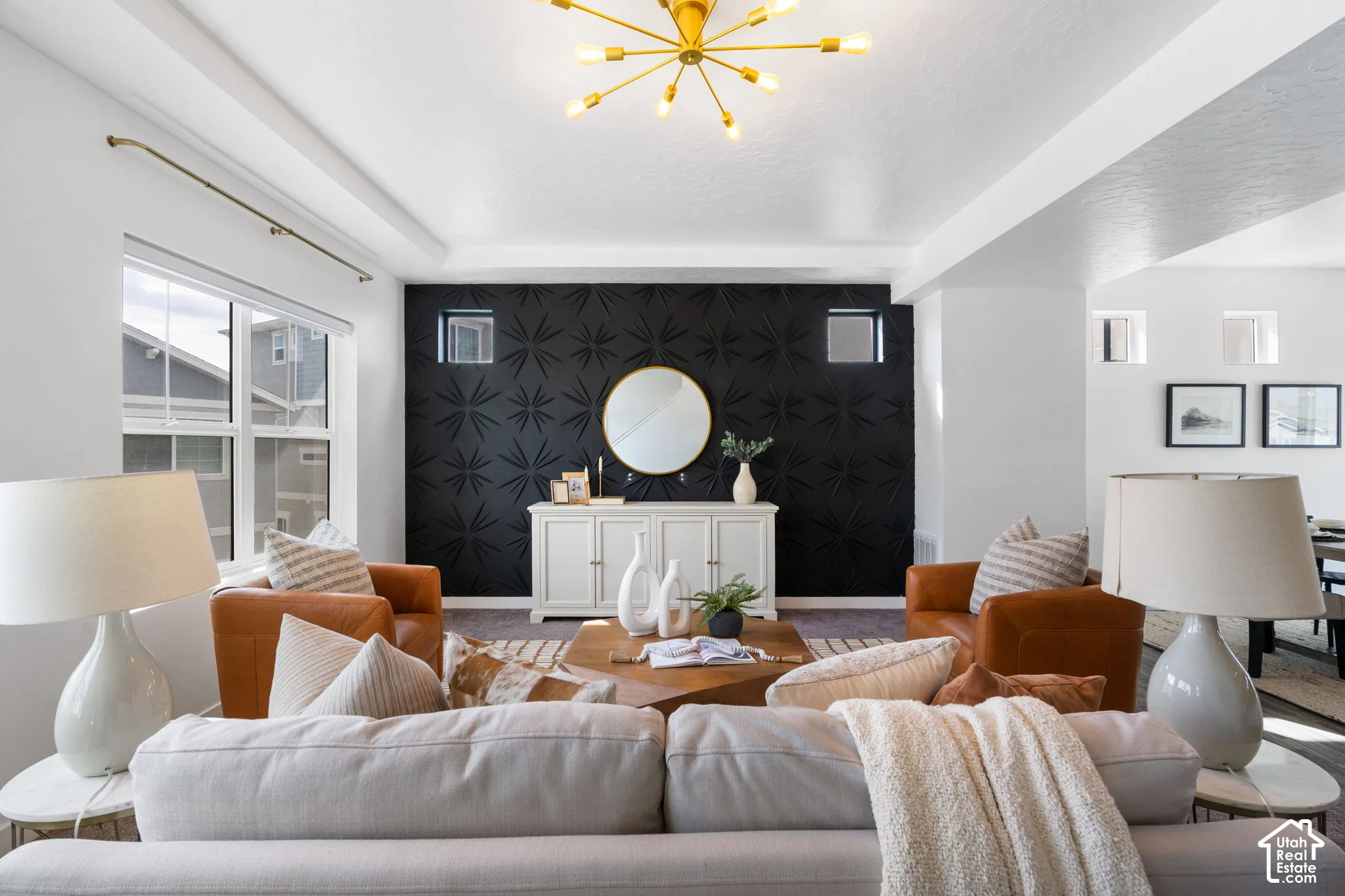 Architectural accent wall, gold sputnik chandelier, coffered ceiling, large windows, and built-in shelving