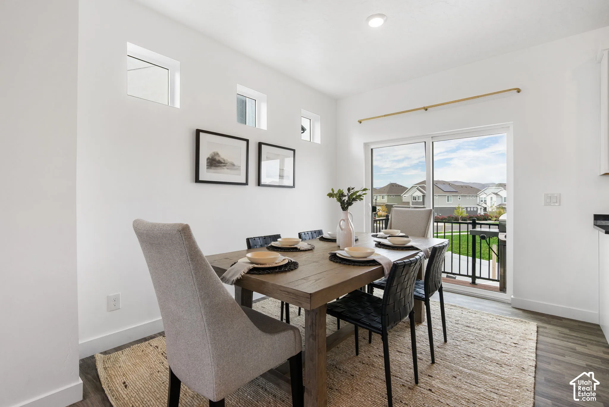 Spacious dining area featuring wood-finish flooring, a sliding glass door to an exterior balcony, and multiple high transom windows