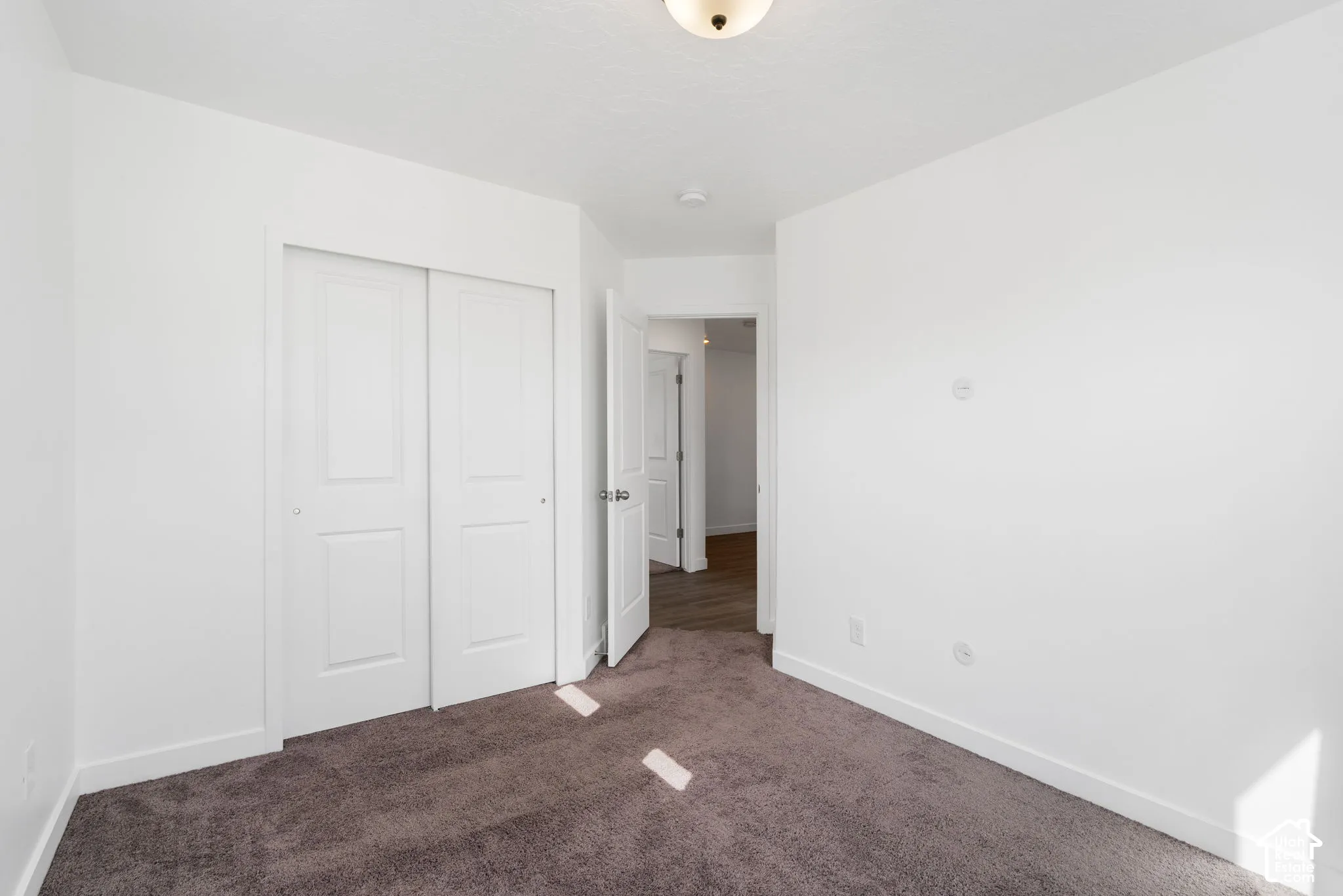 White walls, neutral carpeting, and a flush-mount ceiling light fixture