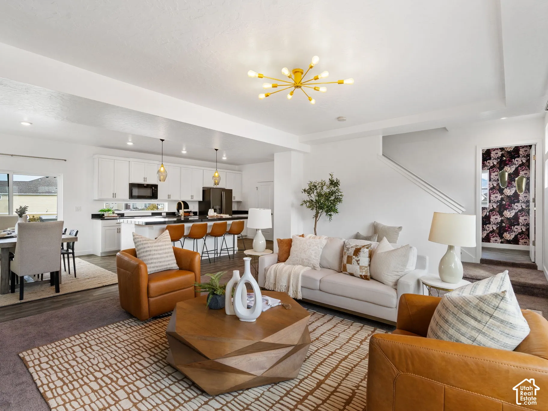 Open-concept living space featuring a modern gold-finish sputnik chandelier, dark wood-finish flooring, white cabinetry, dark countertops, and stainless steel appliances