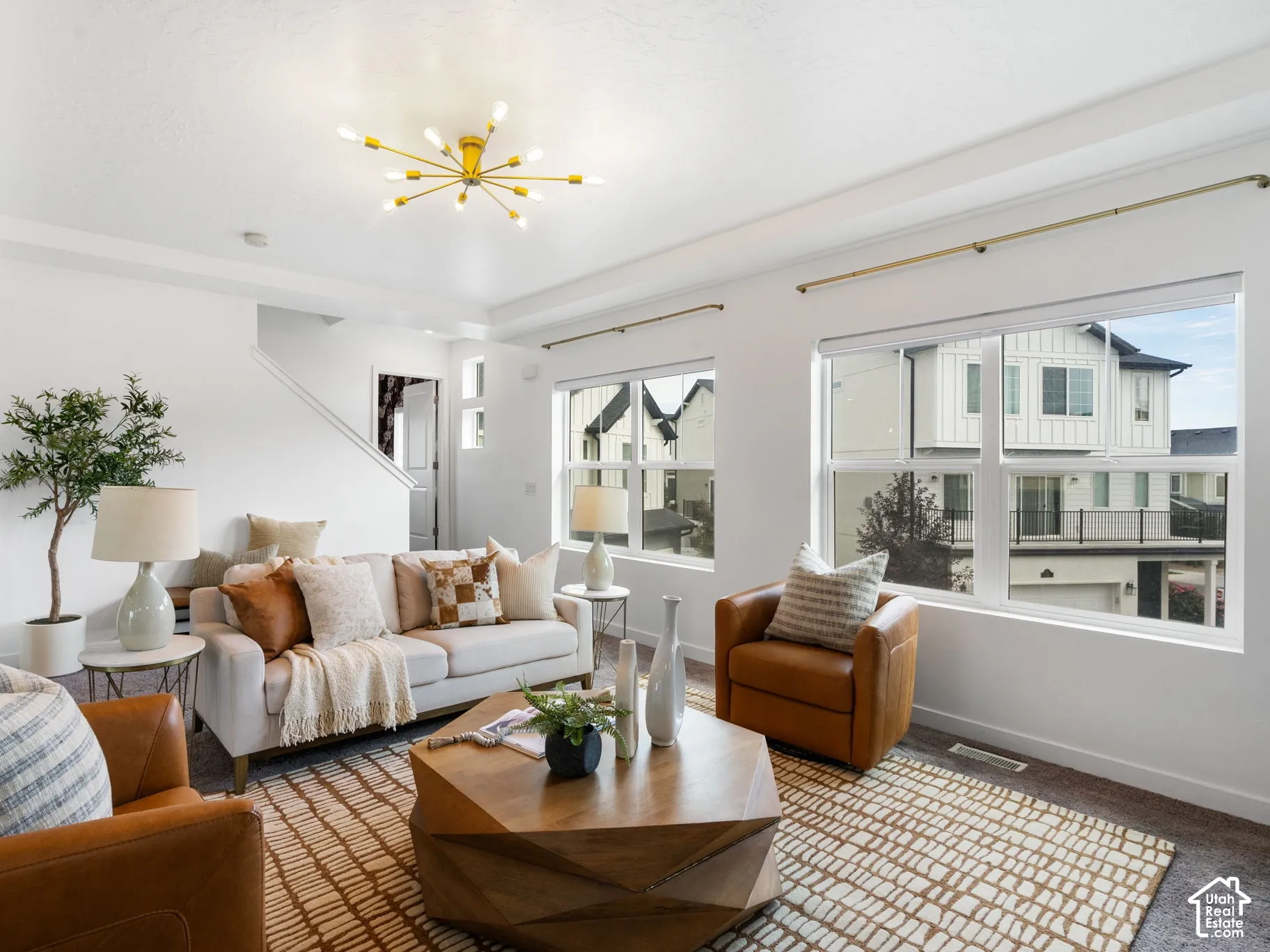 Spacious living area featuring a coffered ceiling, modern sputnik chandelier, large windows, and carpet flooring