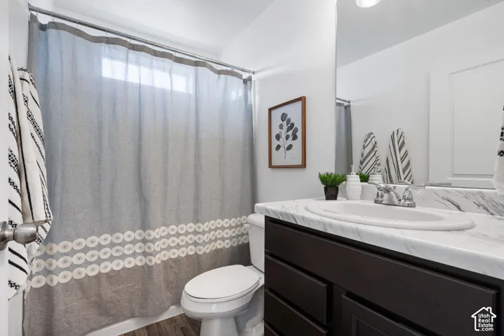 White walls with a window above the shower, dark wood-finish vanity with a white countertop and integrated sink, and an unframed wall mirror