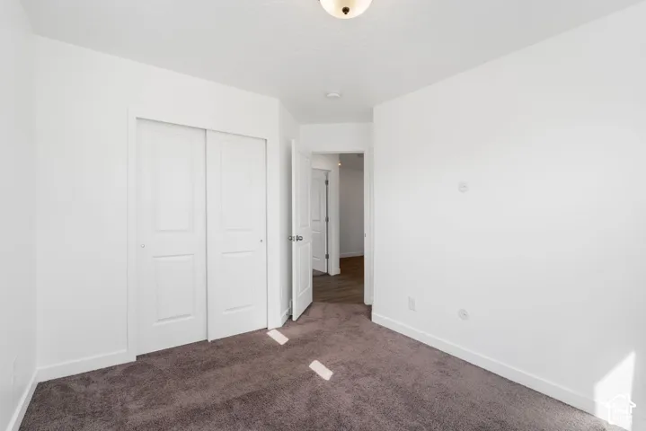 White walls, neutral carpeting, and a flush-mount ceiling light fixture