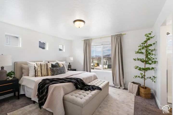 Carpeted flooring, overhead flush mount light, large window with drapes, three high-set windows, white walls