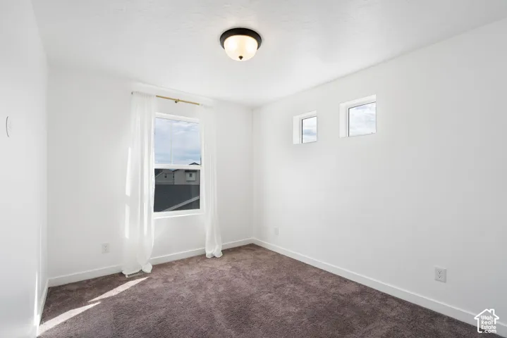 Bright interior featuring white walls, carpet flooring, a flush-mount ceiling light, and multiple windows