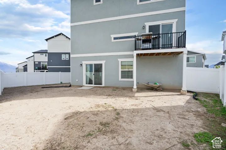 Expansive backyard with a white privacy fence and a second-story balcony featuring black metal railings