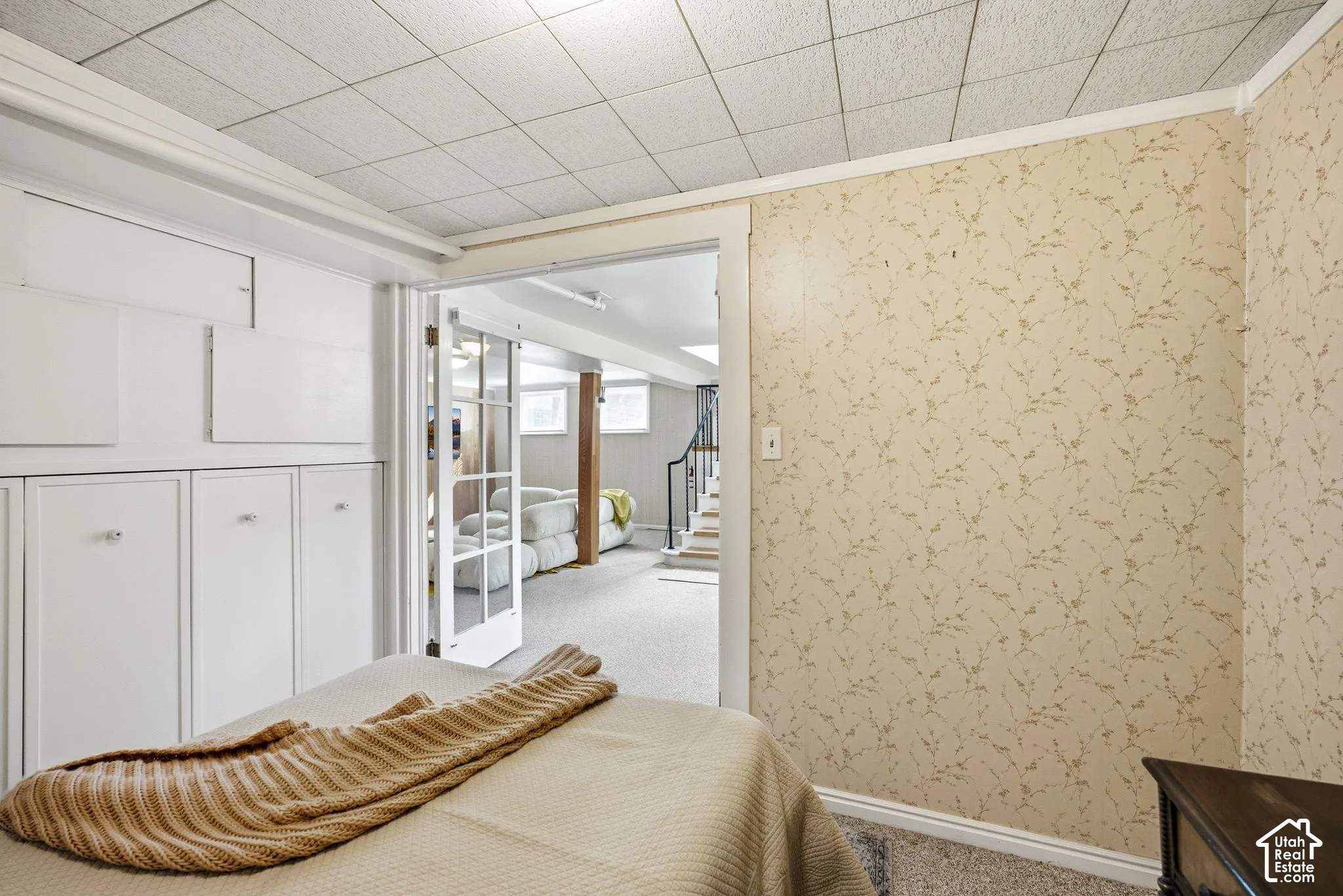 Nonconforming bedroom with wallpapered walls, storage, and a dropped ceiling