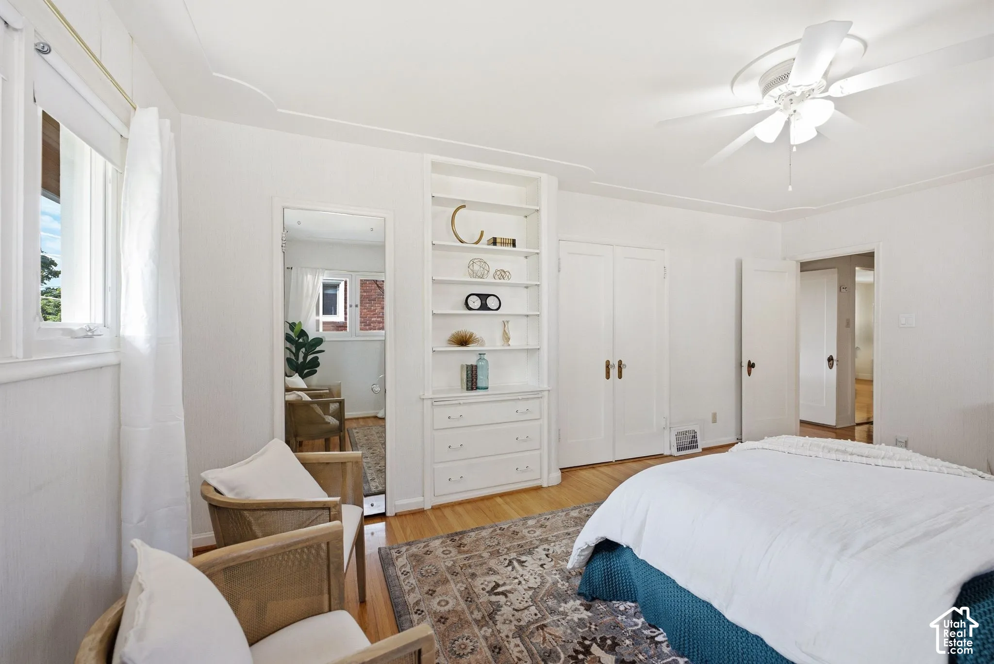 Hardwood flooring, built-in shelving with integrated drawers, ceiling fan, and white trim