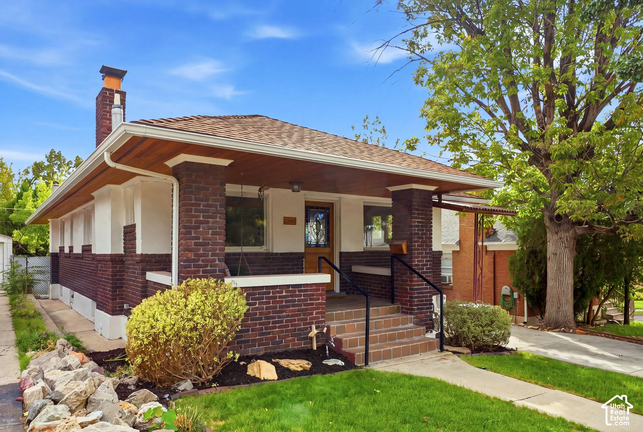 Brick exterior with white trim, covered porch, concrete walkway, and concrete driveway