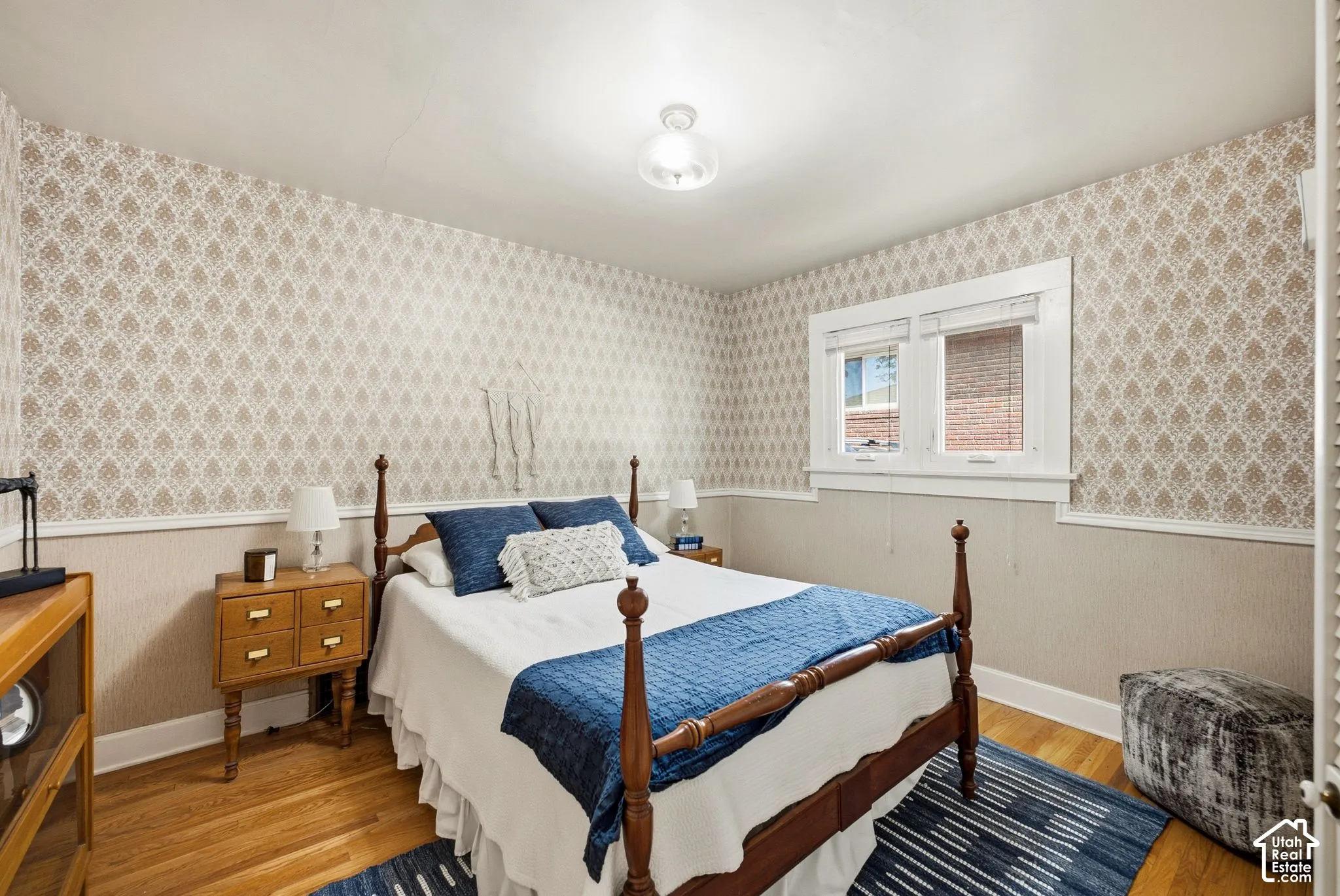 Hardwood flooring, patterned wallpaper, white trim work, and a ceiling-mounted light fixture