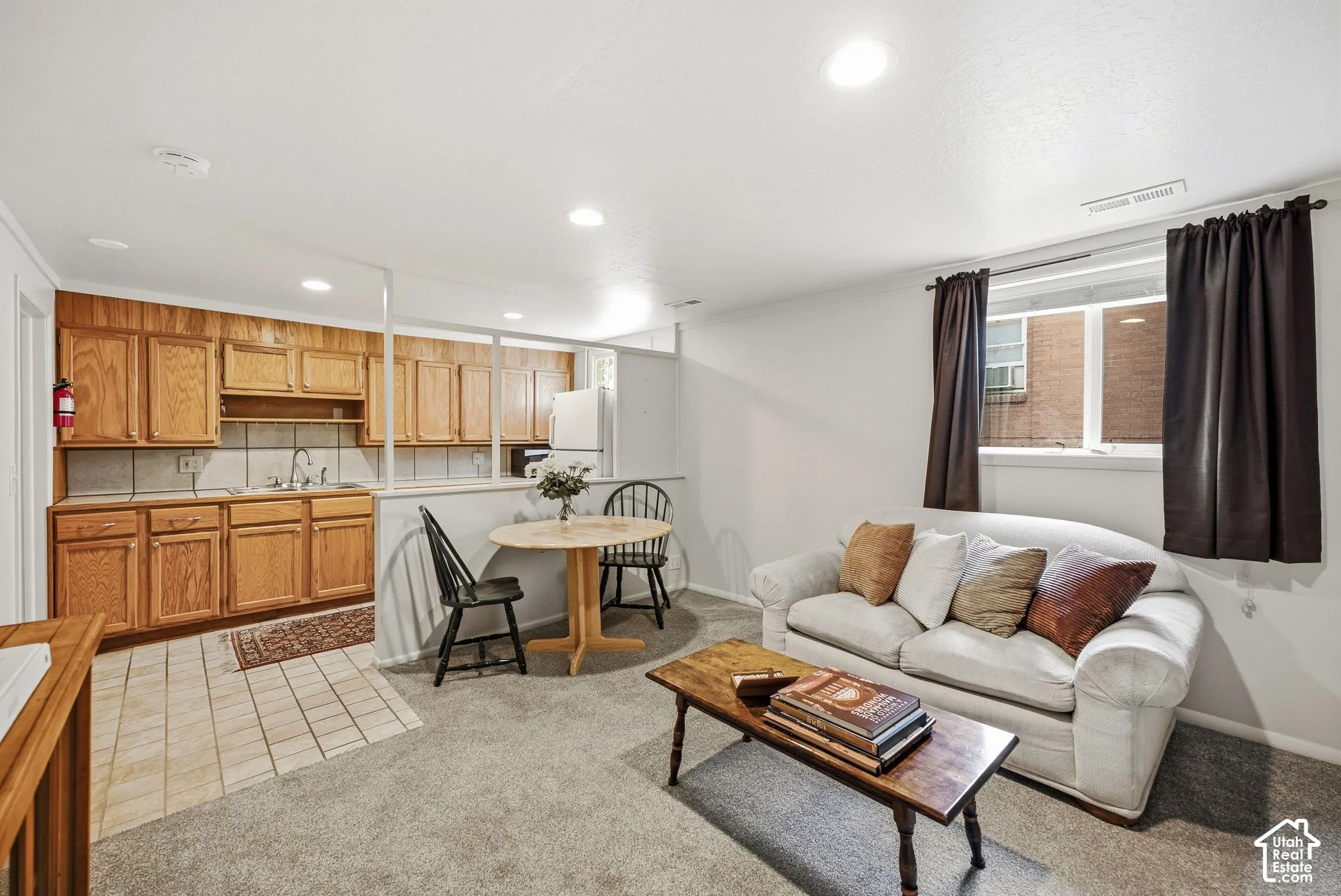 Mother in Law Appt with carpeted living area, recessed lighting, a window, and a kitchen area featuring wood cabinetry, tile backsplash, and tile flooring