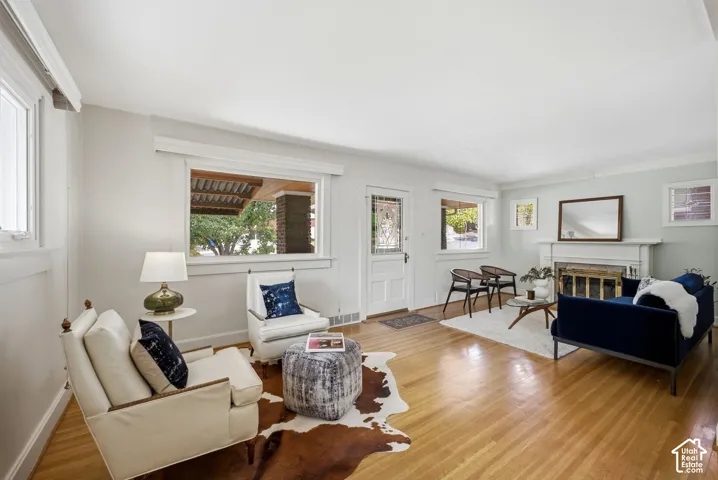 Hardwood flooring, white painted trim, and a fireplace with a mantel