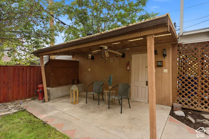 Covered patio area on the side of the garage with wood paneling, a ceiling fan, and recessed lighting