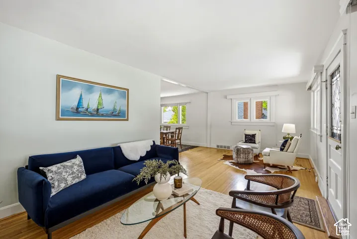Hardwood flooring throughout, white wall finishes, and a decorative front entry door.