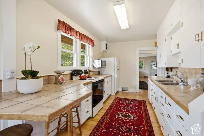 Kitchen featuring white cabinetry, hardwood flooring, and tile countertops