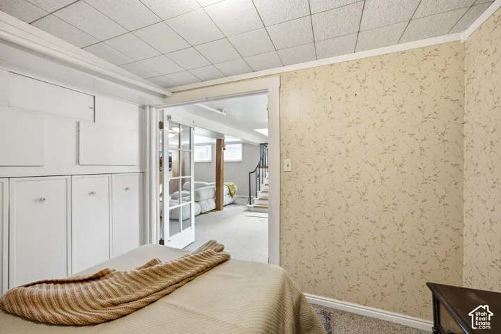Nonconforming bedroom with wallpapered walls, storage, and a dropped ceiling