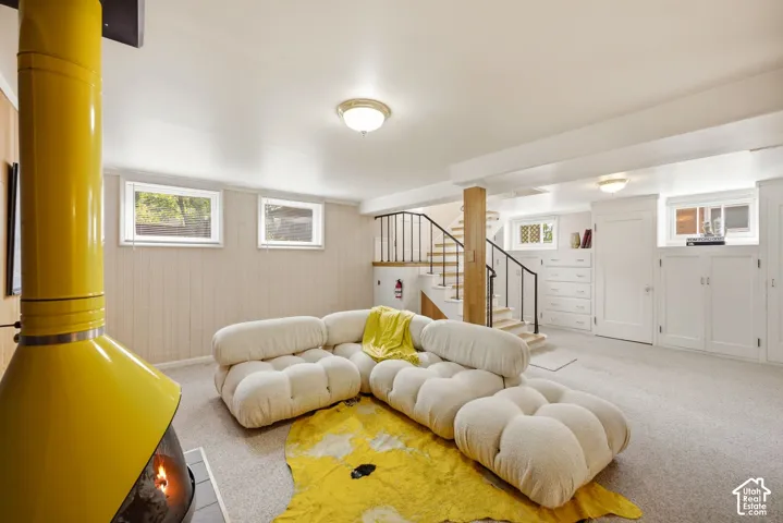 Freestanding yellow fireplace, built-in cabinetry, carpet flooring, and a stairway with black metal railings
