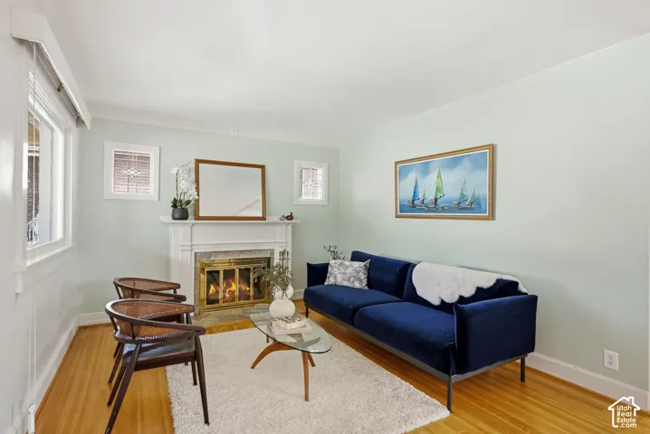 Hardwood flooring, fireplace with a brass-finish insert, white mantel, and light-colored walls