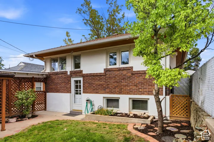 Brick and white exterior with multiple windows, leading to an outdoor patio space