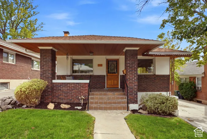Brick and stucco exterior with a covered porch, wood plank ceiling, and a wood-paneled front door