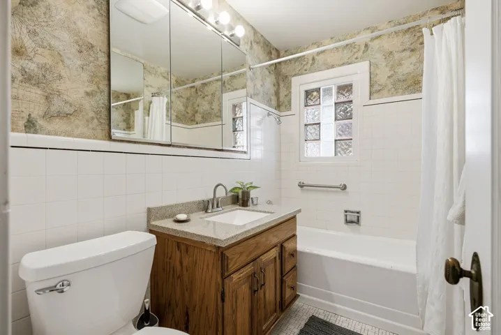 Bathroom featuring a vanity with an integrated sink, a built-in bathtub, glass block window, and a wall-mounted medicine cabinet
