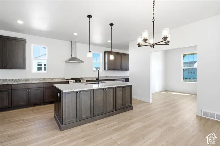 Kitchen featuring dark wood-finish cabinetry, light-toned countertops, and a center island with a sink