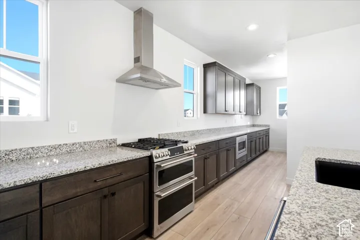 Kitchen featuring extensive granite countertops, stainless steel appliances, dark wood-finish cabinetry, and wood-finish flooring