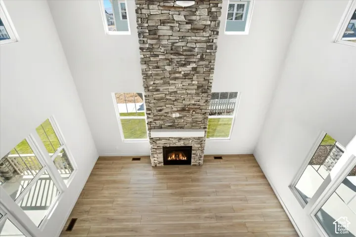 Soaring ceiling with a floor-to-ceiling stone fireplace, wood-finish flooring, and multiple windows