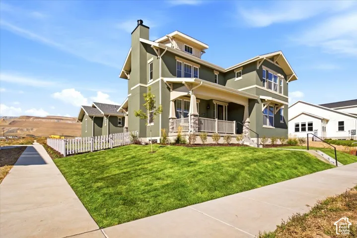 Two-story exterior with a covered front porch, stone column accents, a gabled roofline, and dormer windows