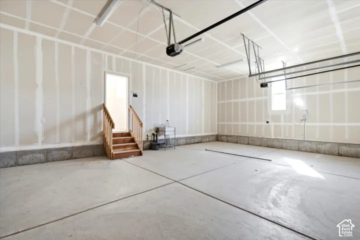 Spacious garage with concrete flooring, automatic garage door openers, internal access door, and utility sink