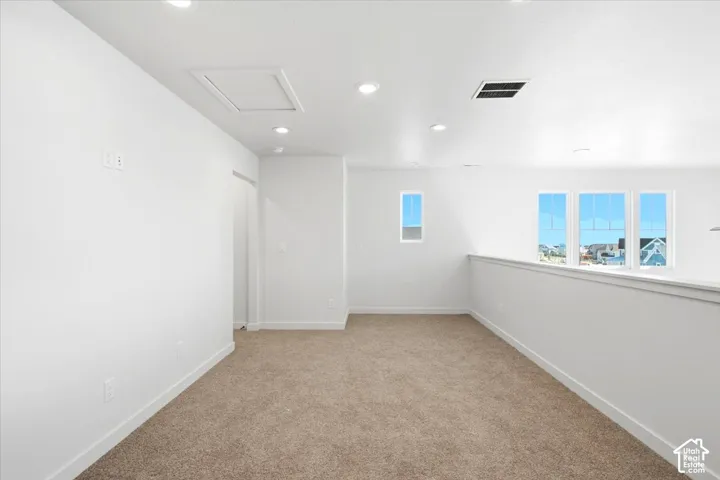 Recessed ceiling lighting, multiple windows, plush carpet flooring, and white painted walls