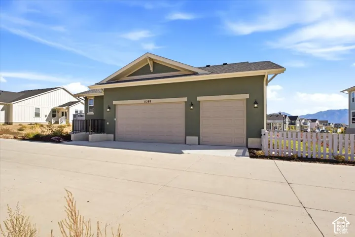 Two-car garage with overhead doors, exterior wall sconces, and a pitched roofline