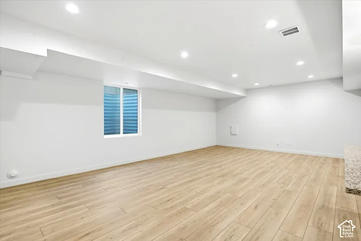 Wood-finish flooring, white walls, and recessed lighting