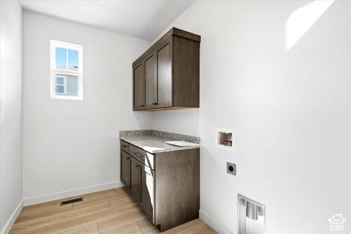 Integrated cabinetry with a stone-finish countertop, wood-finish flooring, and a single window