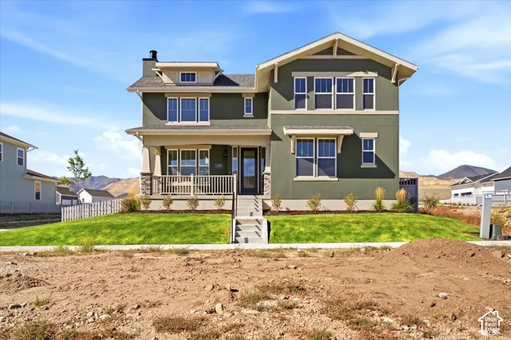 Two-story property with a covered porch featuring stone-clad pillars and a railing