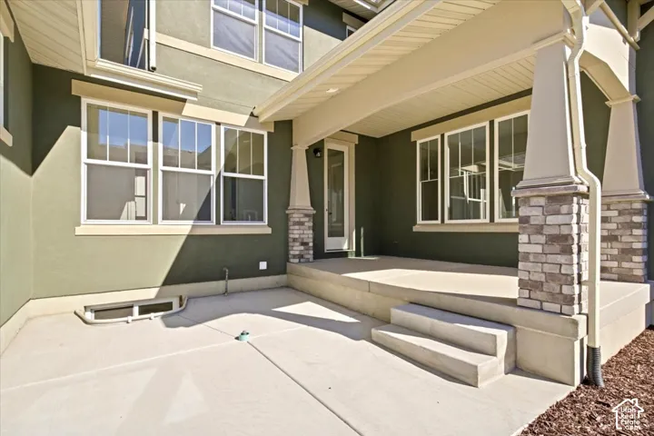 Covered concrete patio with stone-wrapped columns and stucco exterior
