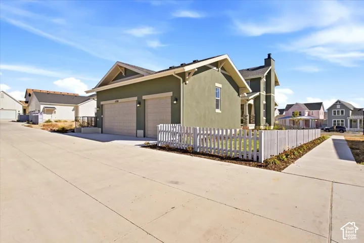 Sage green exterior with white trim, a two-car garage, and a white picket fence