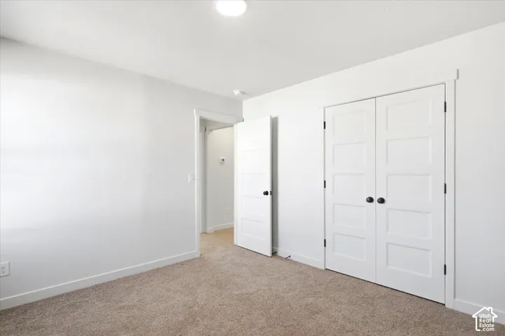 Neutral wall color, carpeted flooring, paneled doors with matte black hardware, recessed lighting, and white trim