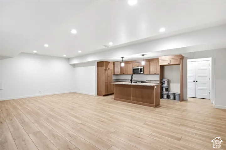 Spacious open-concept area featuring light wood-finish flooring and recessed lighting