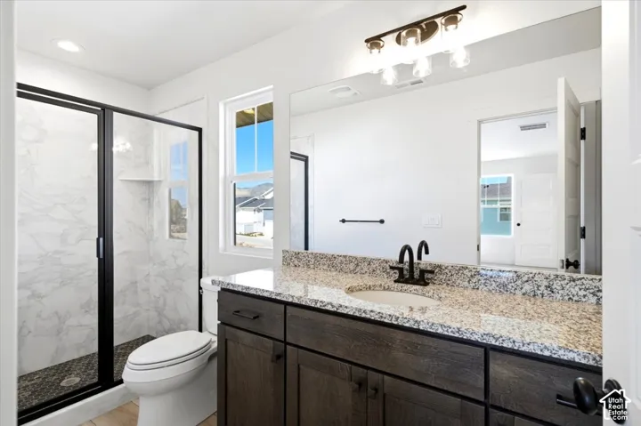 Modern bathroom featuring a walk-in shower with a glass enclosure, a single vanity with stone countertop, and a built-in storage cabinet