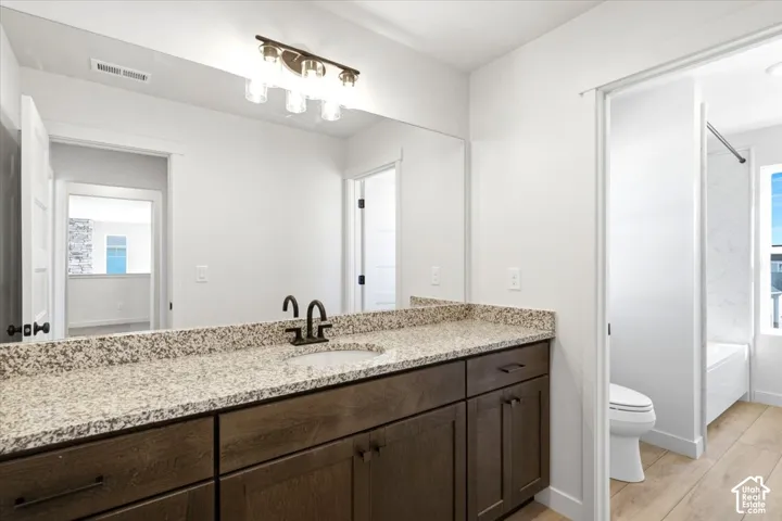 Vanity with a granite-style countertop, undermount sink, and dark wood-finish cabinetry