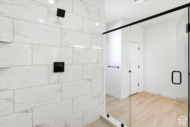 Spacious shower with large format white tile, matte black fixtures, and a frameless glass enclosure