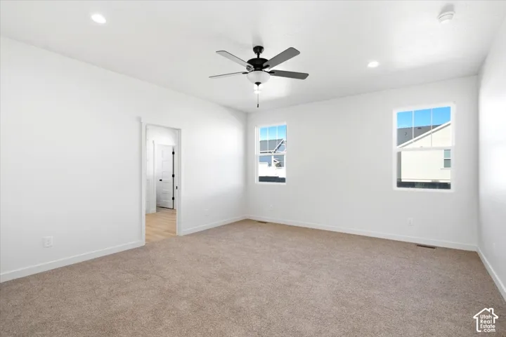 Room featuring neutral carpet, white walls, two windows, a ceiling fan, and recessed lighting