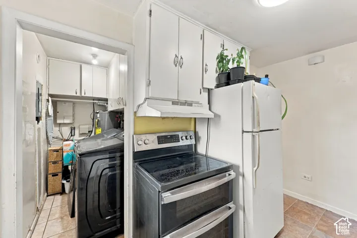 Kitchen area featuring white cabinetry, a built-in range hood, a stainless steel electric stove, and tile flooring