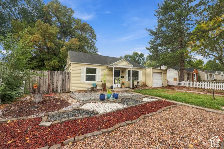 Exterior featuring light-colored siding, attached garage, white shutters, front entrance portico, and decorative hardscaping